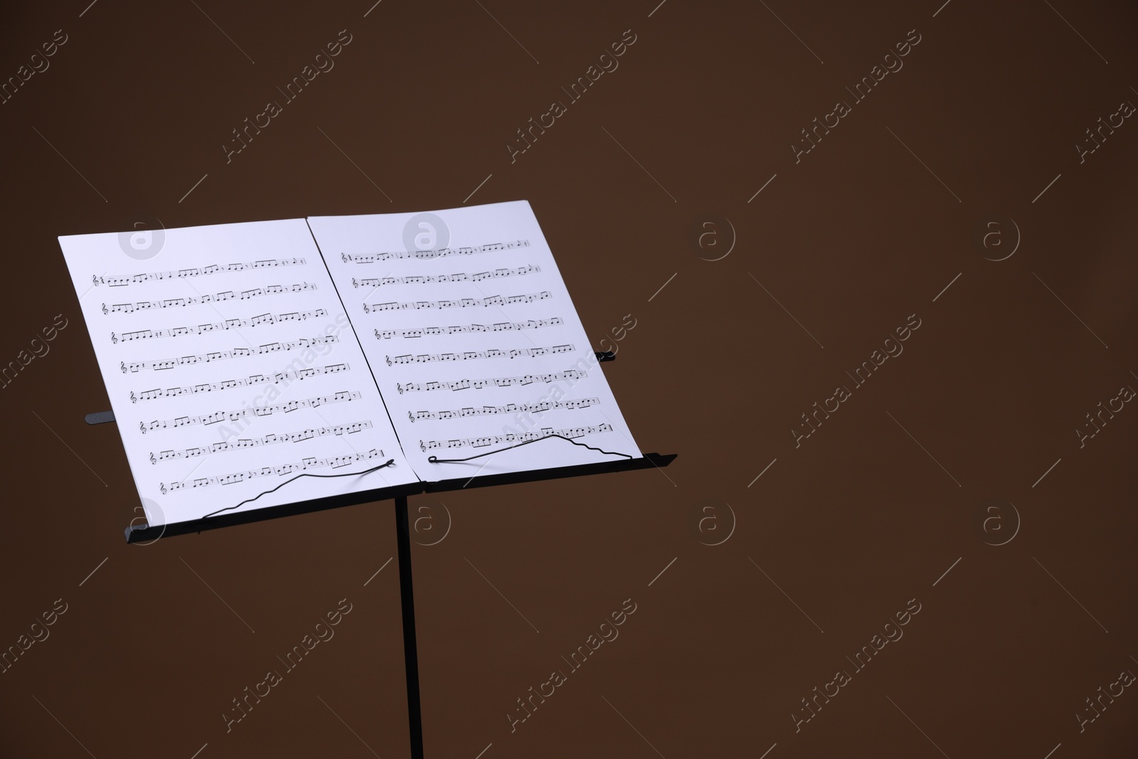 Stand with music sheets on brown background, space for text Photo of Stand with music sheets on brown background, space for text