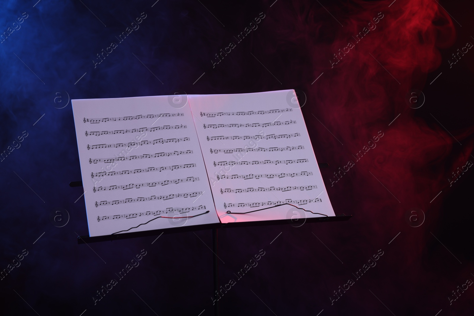 Stand with music sheets on dark background with smoke Photo of Stand with music sheets on dark background with smoke