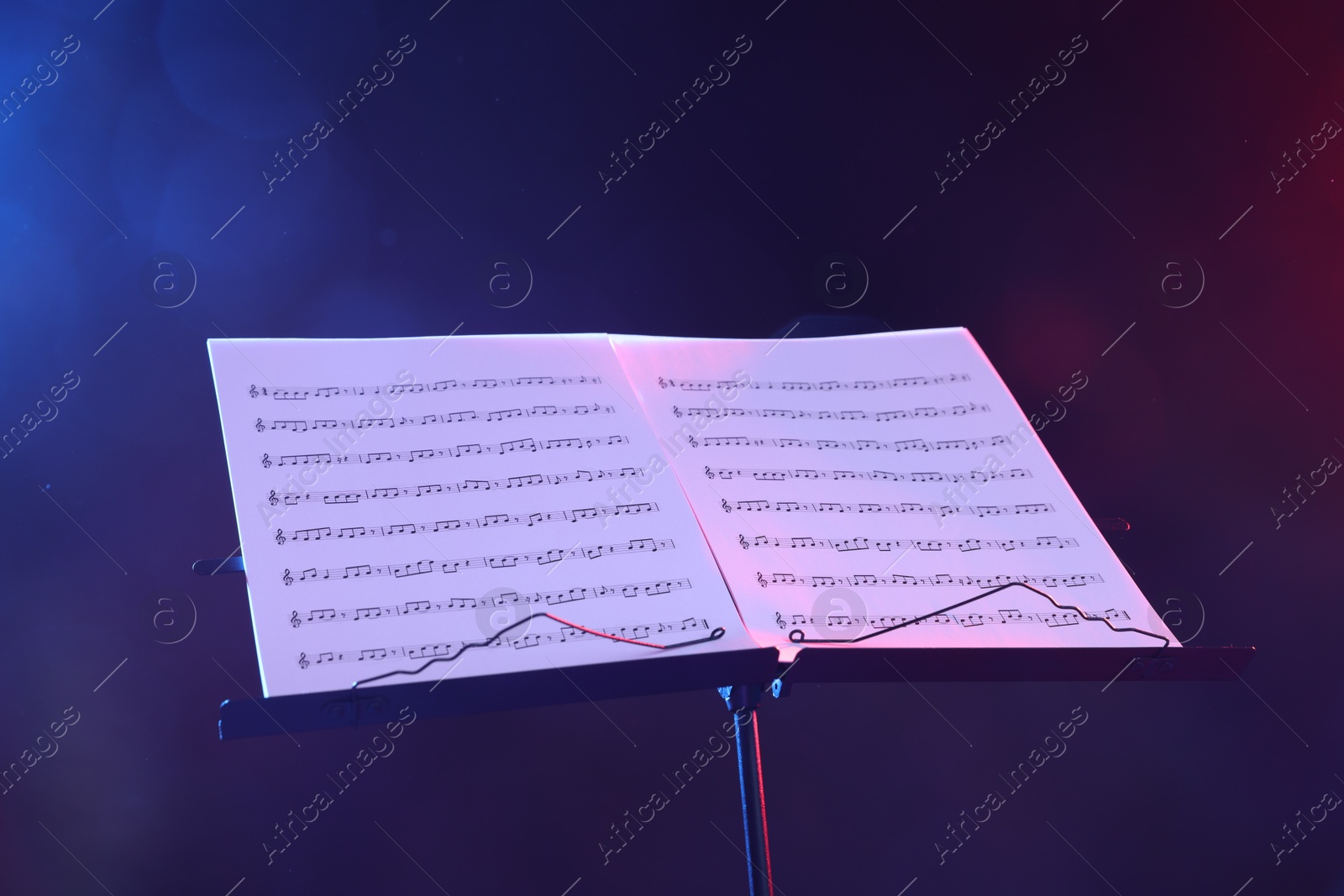 Stand with music sheets in neon lights on dark background, closeup Photo of Stand with music sheets in neon lights on dark background, closeup