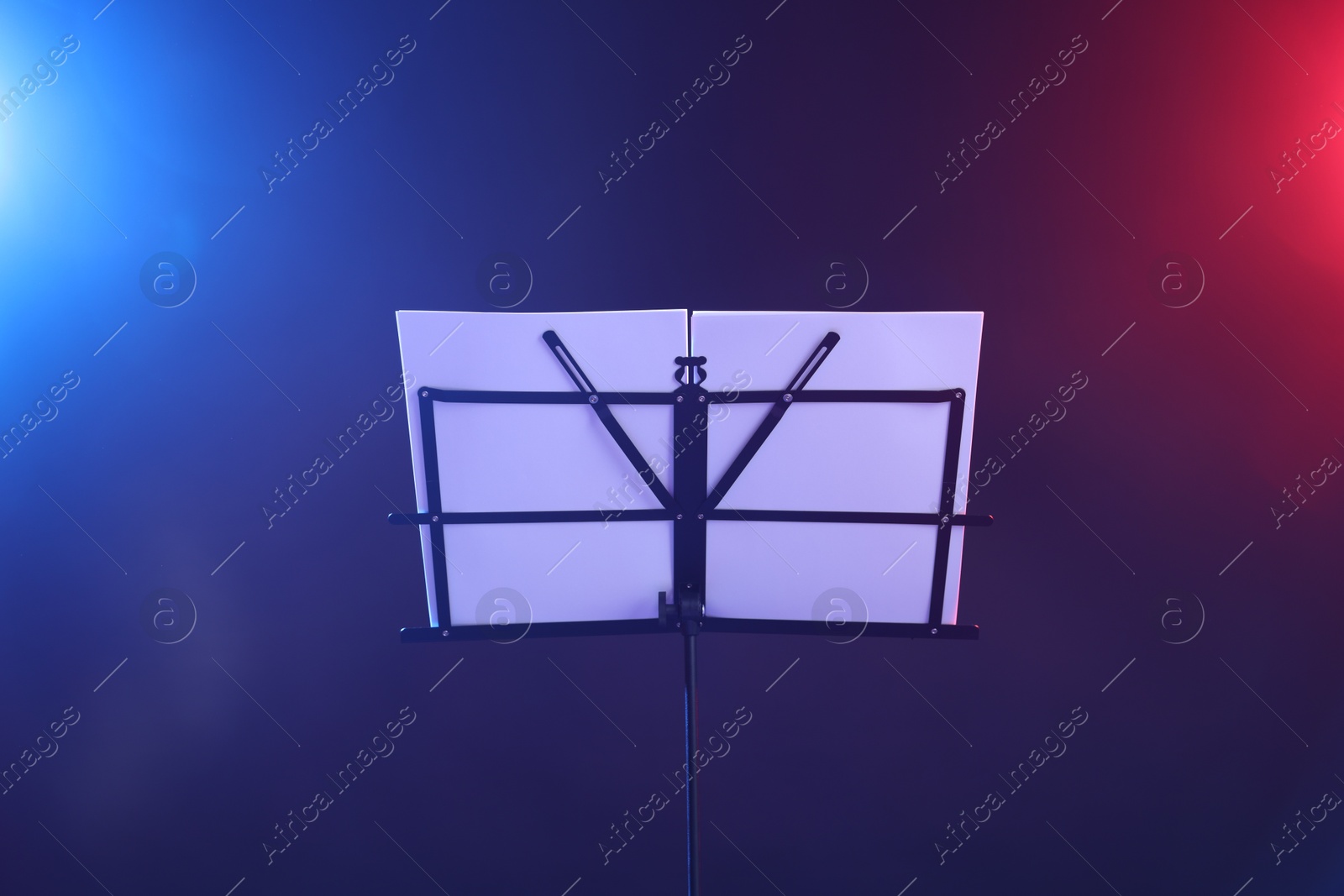 Stand with music sheets in neon lights on dark background Photo of Stand with music sheets in neon lights on dark background