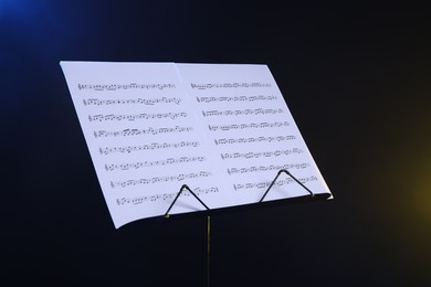 Photo of Stand with music sheets on dark background, closeup