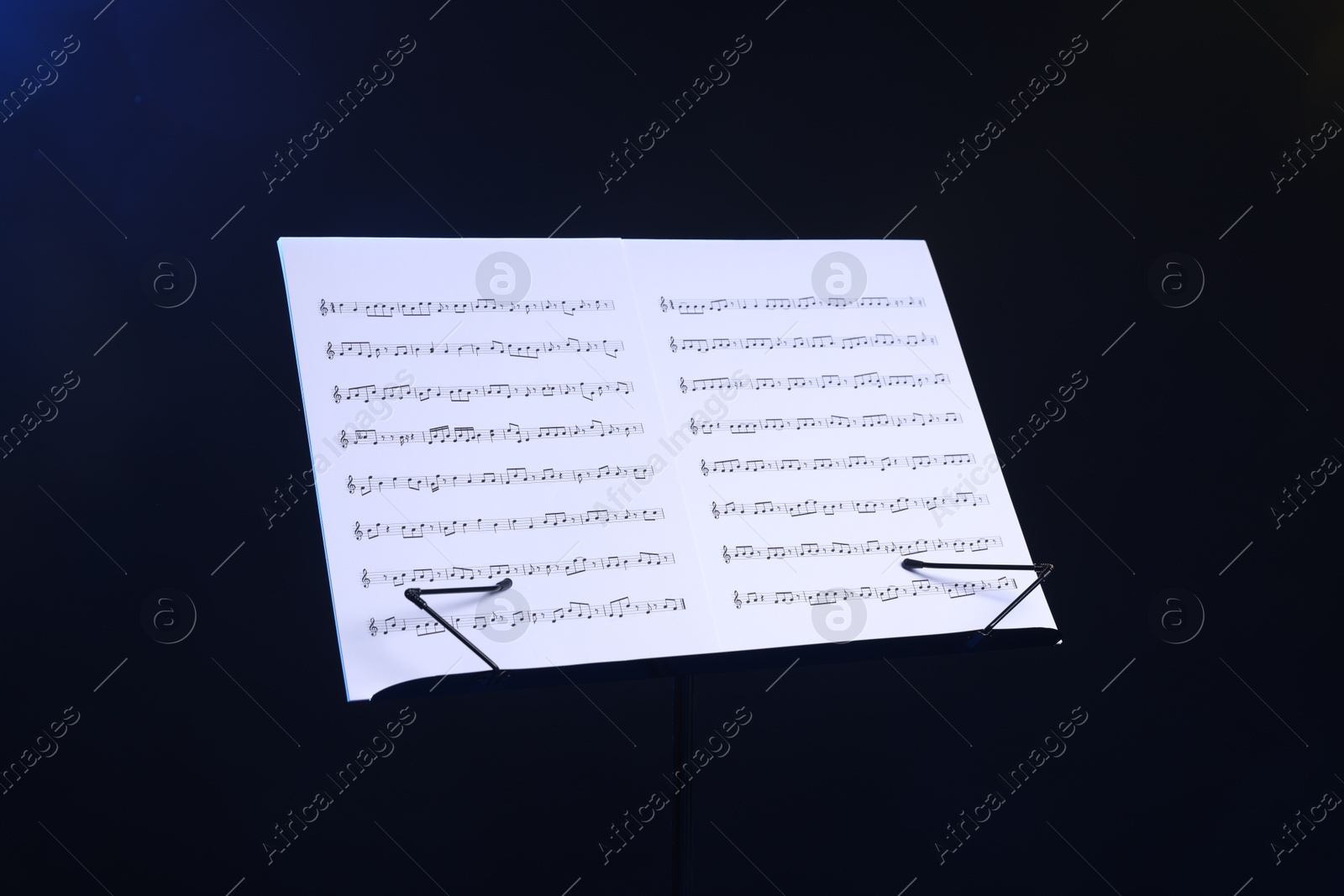 Stand with music sheets on dark blue background Photo of Stand with music sheets on dark blue background
