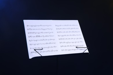 Photo of Stand with music sheets on dark blue background