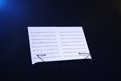 Photo of Stand with music sheets on dark blue gradient background