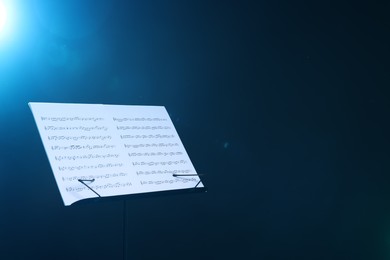 Photo of Stand with music sheets on dark blue gradient background, space for text