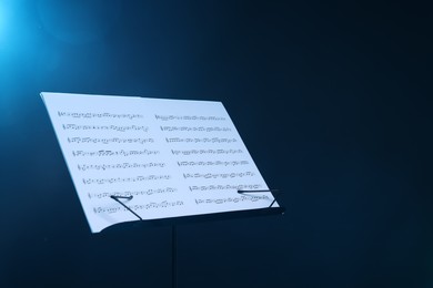 Photo of Stand with music sheets on dark blue gradient background, space for text