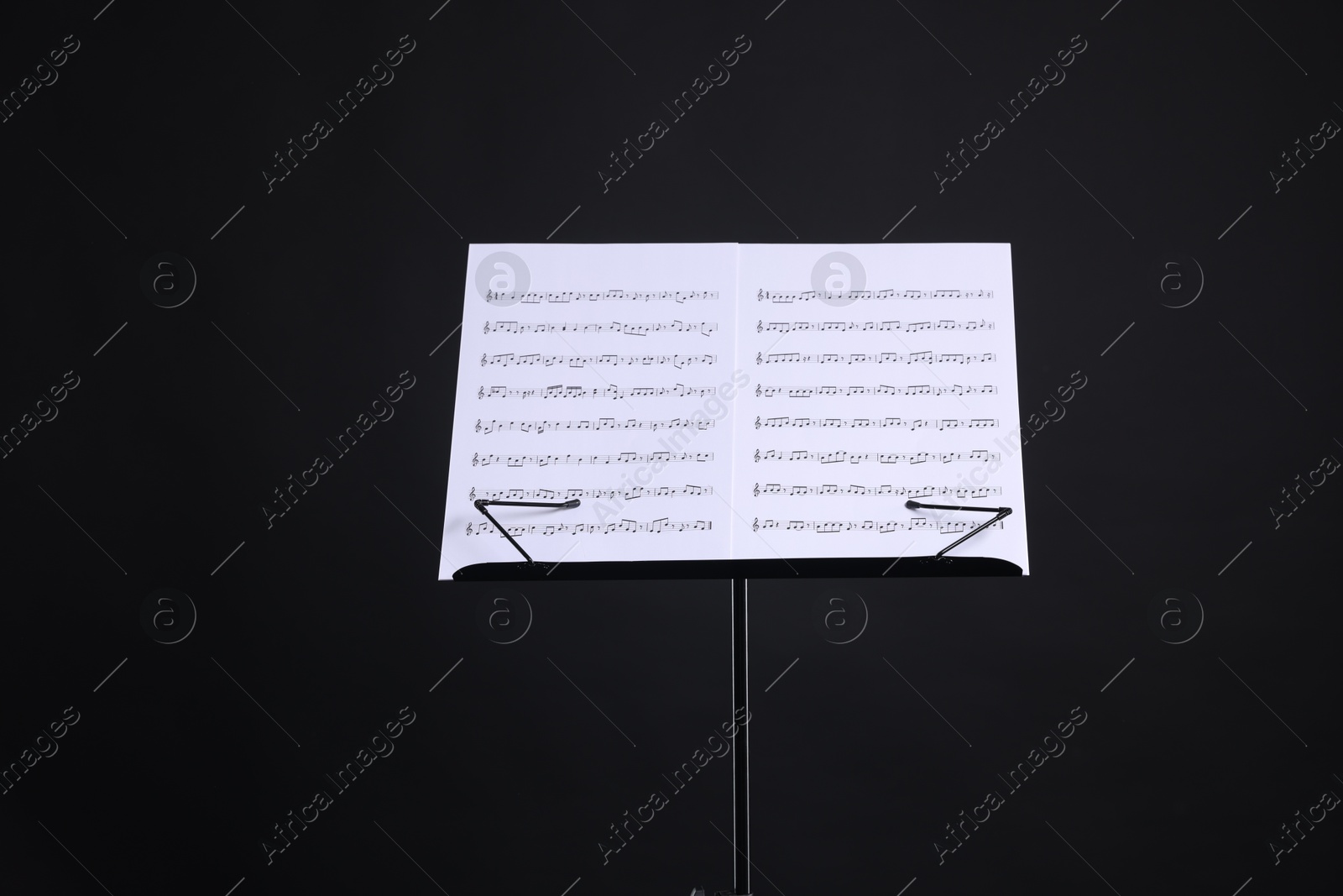 Stand with music sheets on black background Photo of Stand with music sheets on black background