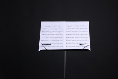 Photo of Stand with music sheets on black background