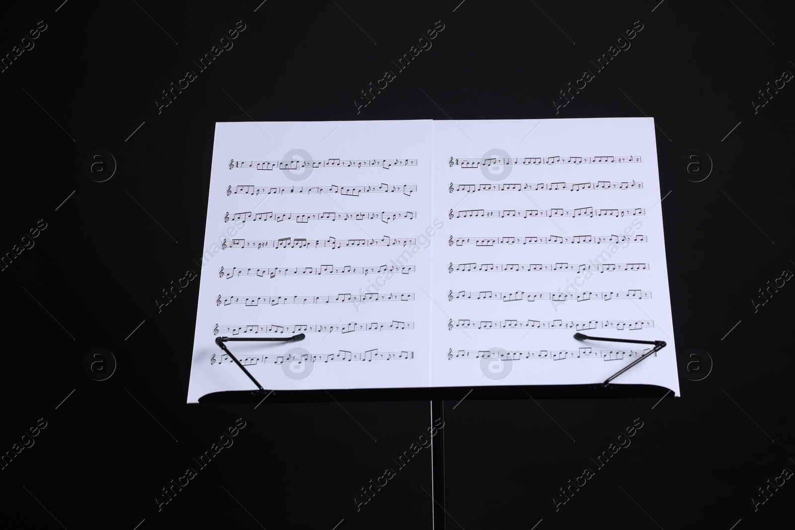 Stand with music sheets on black background Photo of Stand with music sheets on black background