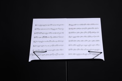 Photo of Stand with music sheets on black background