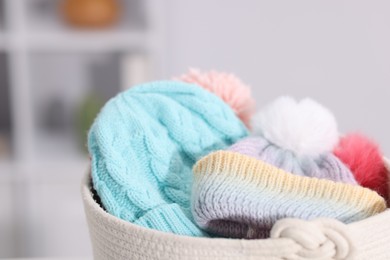 Photo of Different wool hats in basket indoors, closeup