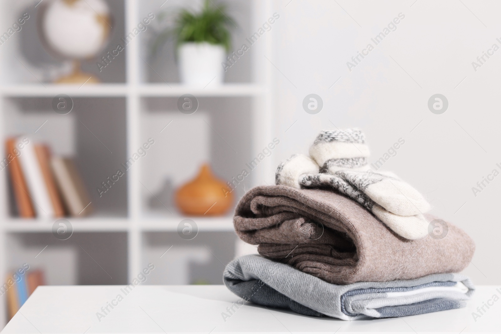 Stack of wool clothes on white table indoors, space for text Photo of Stack of wool clothes on white table indoors, space for text
