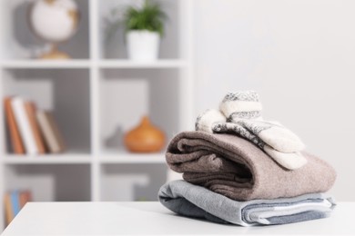 Photo of Stack of wool clothes on white table indoors, space for text