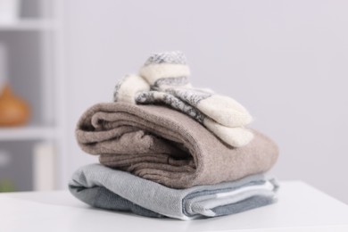 Photo of Stack of wool clothes on white table indoors
