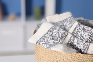 Photo of Warm wool socks in wicker basket indoors, closeup. Space for text