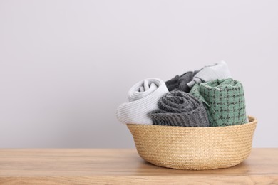 Photo of Wool scarves in wicker basket on wooden table indoors, space for text