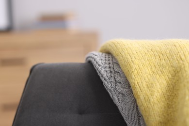 Photo of Color wool sweaters on armchair indoors, closeup
