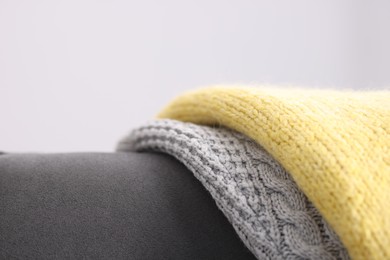 Photo of Color wool sweaters on armchair against light background, closeup