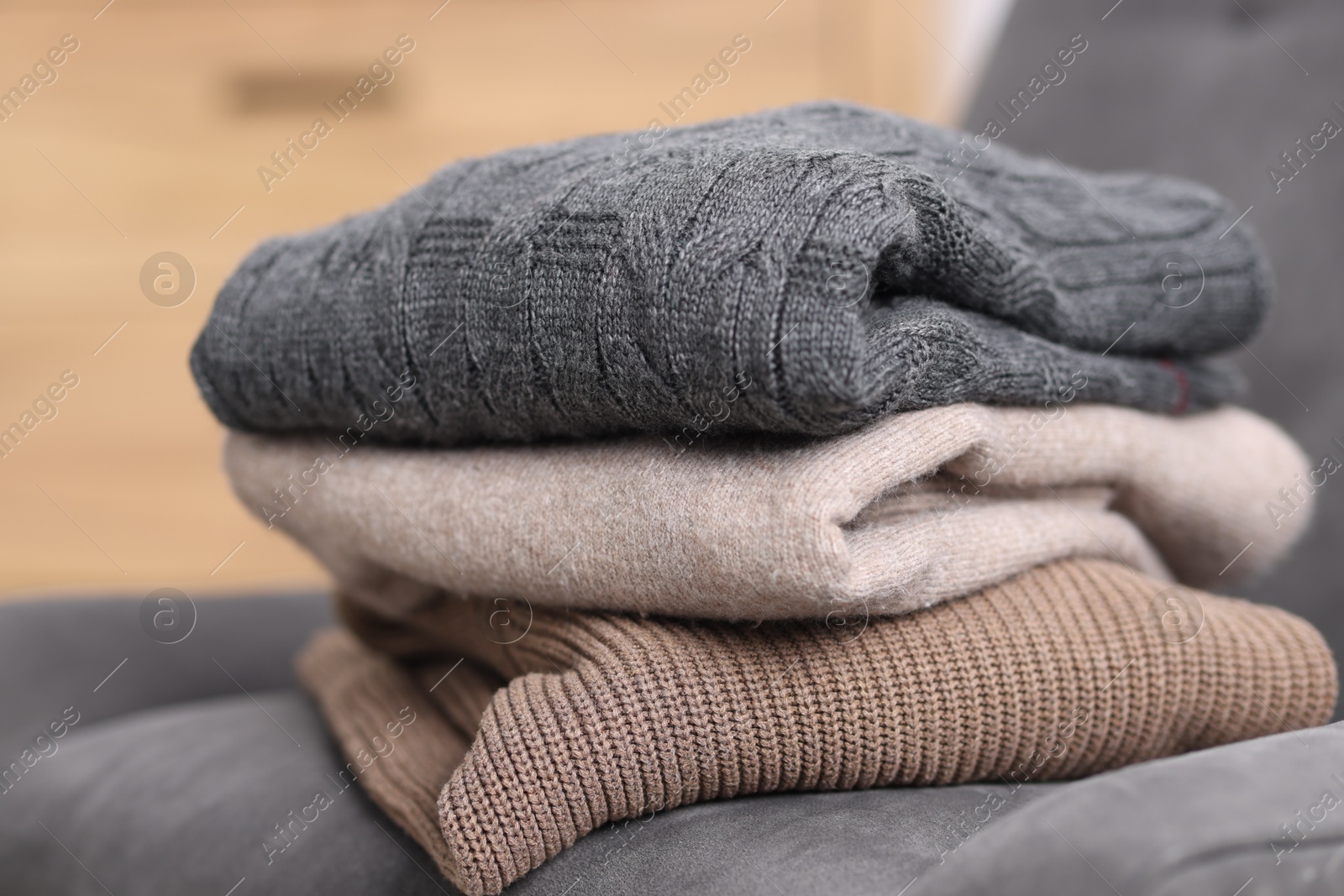 Folded wool sweaters on armchair indoors, closeup Photo of Folded wool sweaters on armchair indoors, closeup