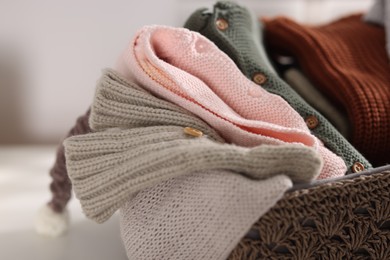 Photo of Wool baby clothes in basket on table indoors, closeup