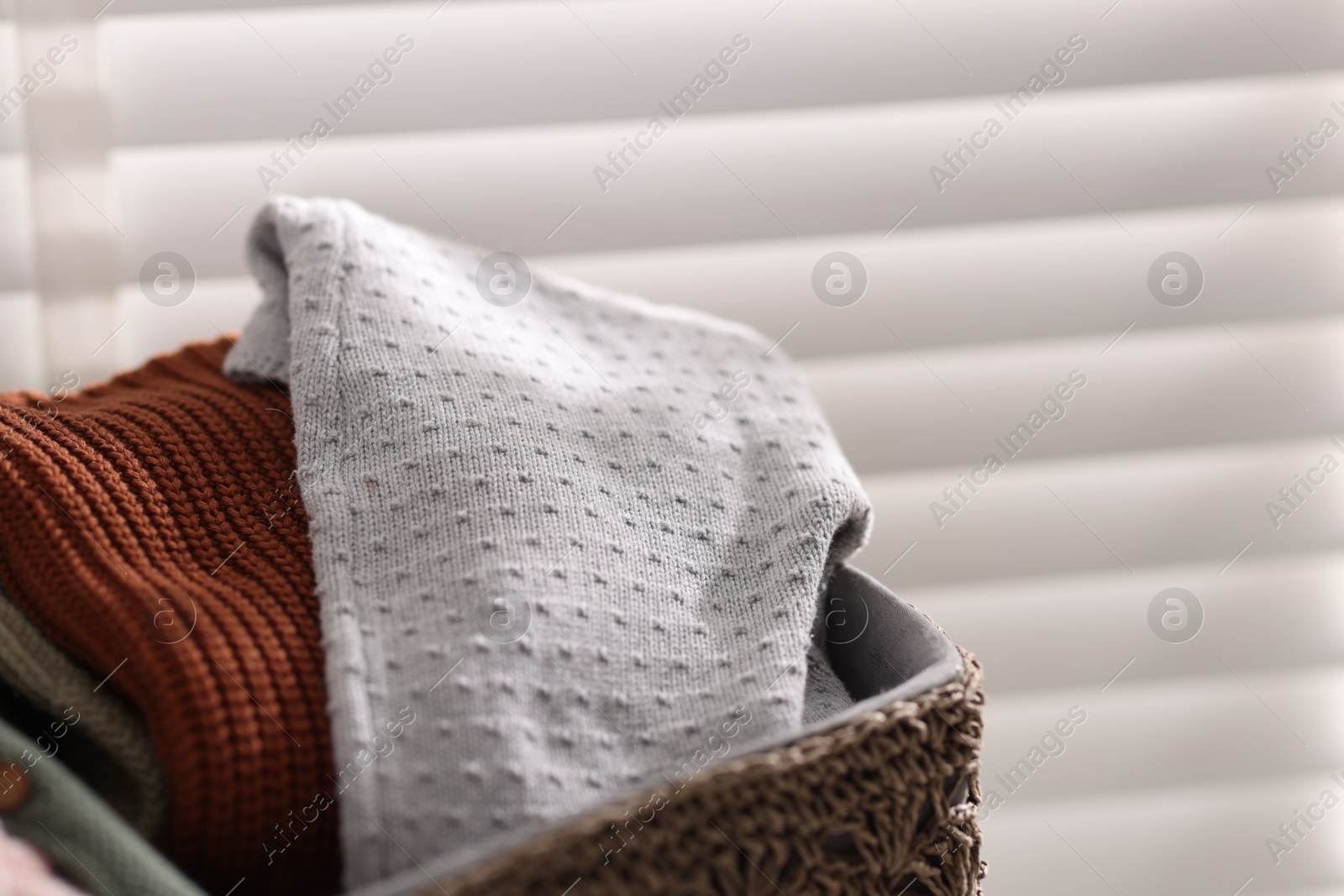 Wool baby clothes in basket on light background, closeup Photo of Wool baby clothes in basket on light background, closeup