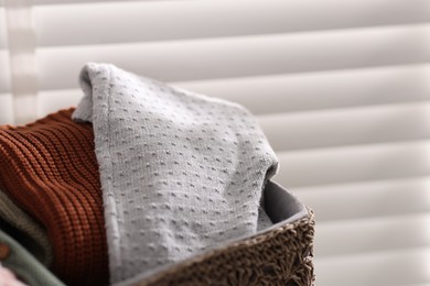 Photo of Wool baby clothes in basket on light background, closeup