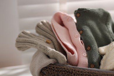 Photo of Wool baby clothes in basket on light background, closeup