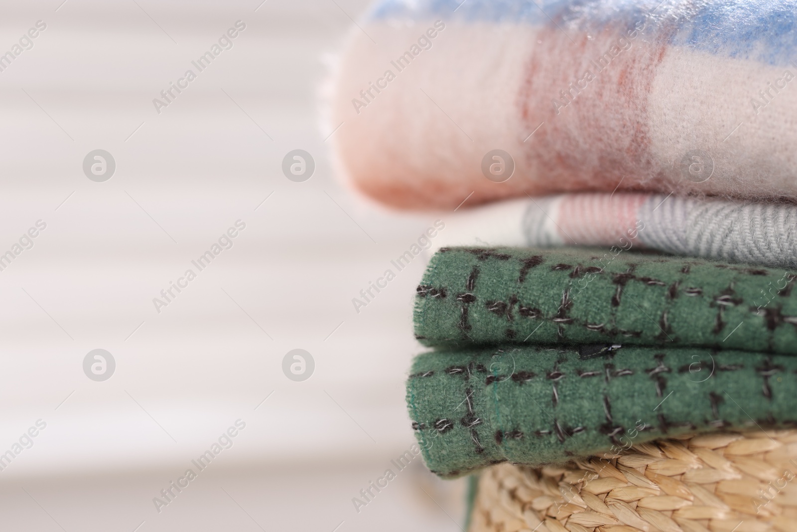 Wool scarves on wicker box against light background, closeup. Space for text Photo of Wool scarves on wicker box against light background, closeup. Space for text
