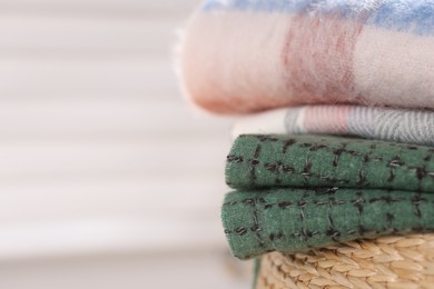 Photo of Wool scarves on wicker box against light background, closeup. Space for text