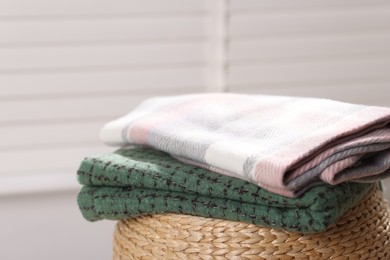 Photo of Wool scarves on wicker box indoors, closeup