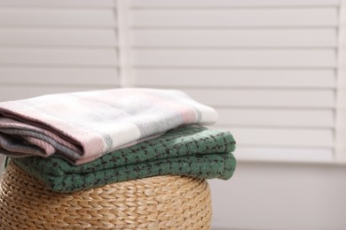 Photo of Wool scarves on wicker box indoors, closeup. Space for text