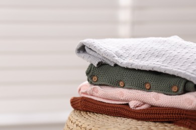 Photo of Wool baby clothes on wicker box indoors, closeup. Space for text