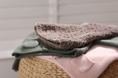 Photo of Wool baby clothes on wicker box against light background, closeup