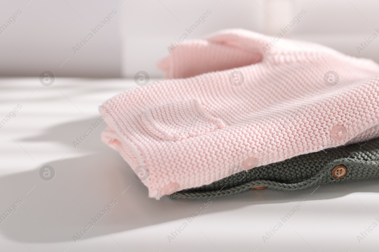 Wool baby sweaters on white table indoors, closeup Photo of Wool baby sweaters on white table indoors, closeup