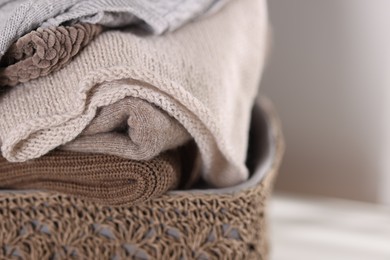 Photo of Wool sweaters in basket on light background, closeup