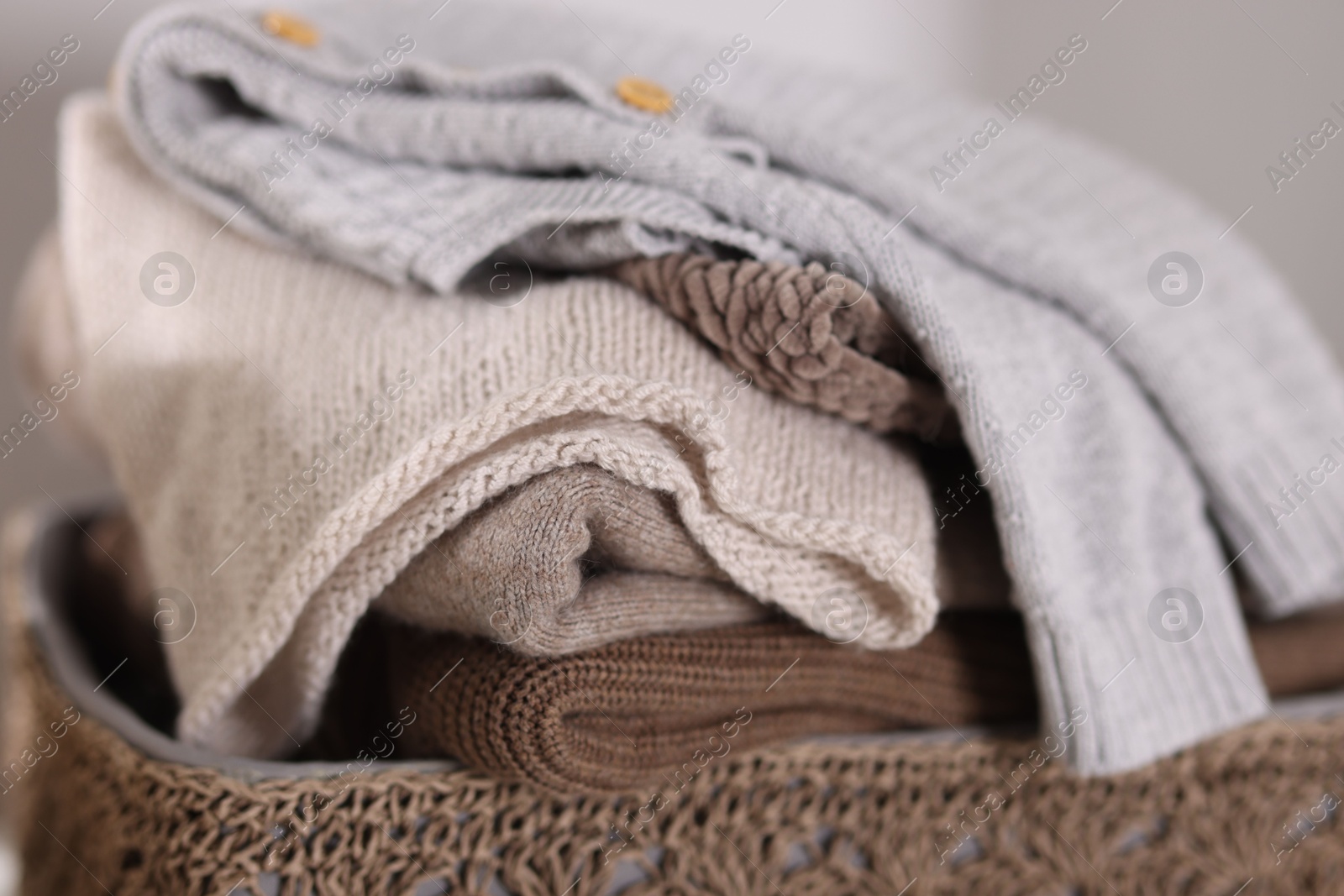 Wool sweaters in basket on light background, closeup Photo of Wool sweaters in basket on light background, closeup