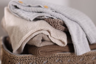 Photo of Wool sweaters in basket on light background, closeup