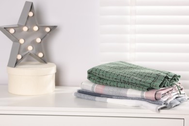 Photo of Wool scarves, box and star shaped lamp on white nightstand indoors