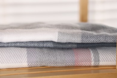 Photo of Wool scarves on wooden shelf indoors, closeup