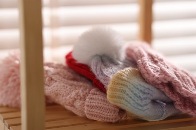 Photo of Wool hats on wooden shelf indoors, closeup