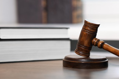 Photo of Judge. Gavel and books on wooden table in office, closeup