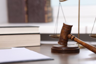 Photo of Judge. Gavel, scales, clipboard and books on wooden table in office, selective focus