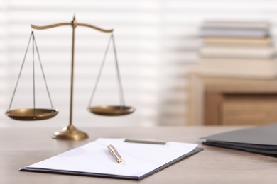 Photo of Judge. Scales, clipboard, pen and folders on wooden table in office, selective focus