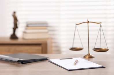 Photo of Judge. Scales, clipboard, pen and folders on wooden table in office, selective focus
