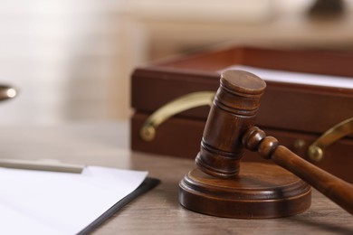 Photo of Judge. Gavel and clipboard on wooden table in office, closeup