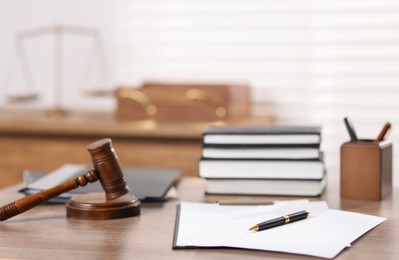 Photo of Judge. Gavel, books, papers and pen on wooden table in office, selective focus