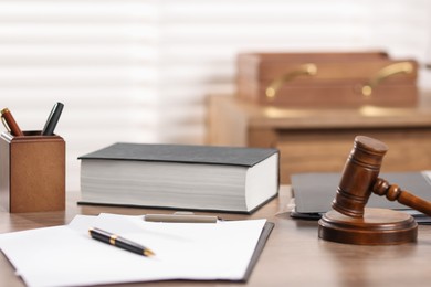 Photo of Judge. Gavel, book, papers and pen on wooden table in office