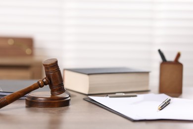 Photo of Judge. Gavel, book, papers and pen on wooden table in office, selective focus