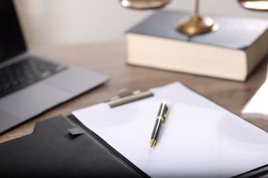 Photo of Judge. Laptop, clipboard, pen, book and scales on wooden table in office, closeup