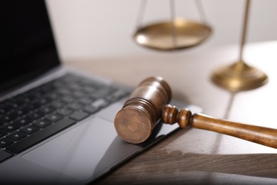 Photo of Judge. Laptop, gavel and scales on wooden table in office, closeup